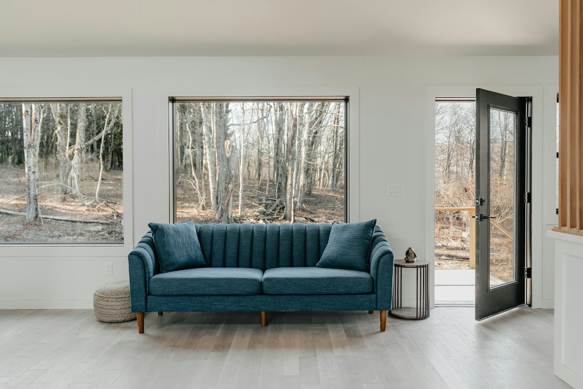 Sala iluminada com sofá azul e decoração contemporânea.
